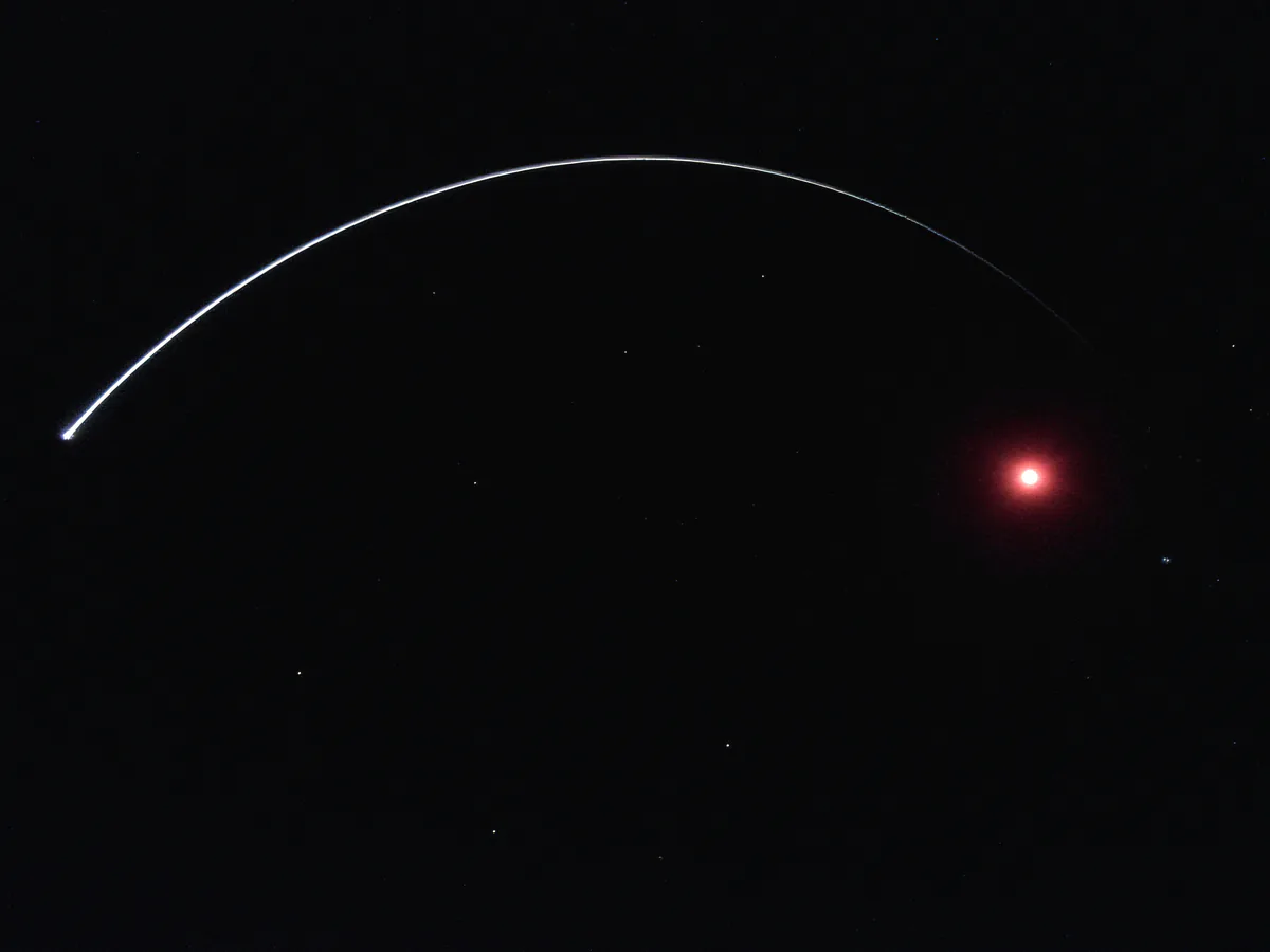Slingshot: a white spark launched across a bent grid of space toward the red star Antares